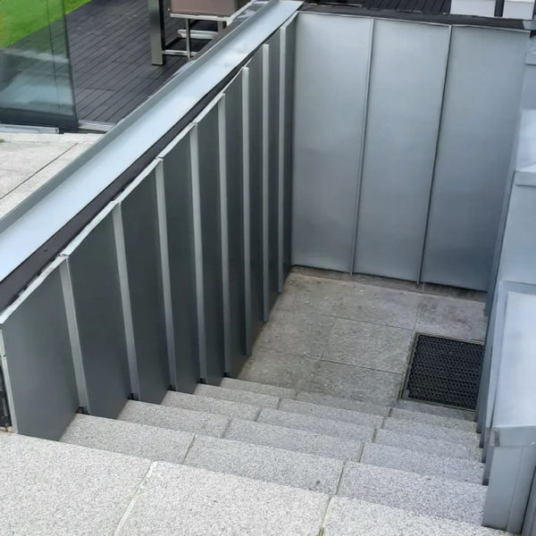 Ein Kellerabgang an einer Terrasse mit einer Mauerabdeckung und Wandverkleidung aus Zinkblech.