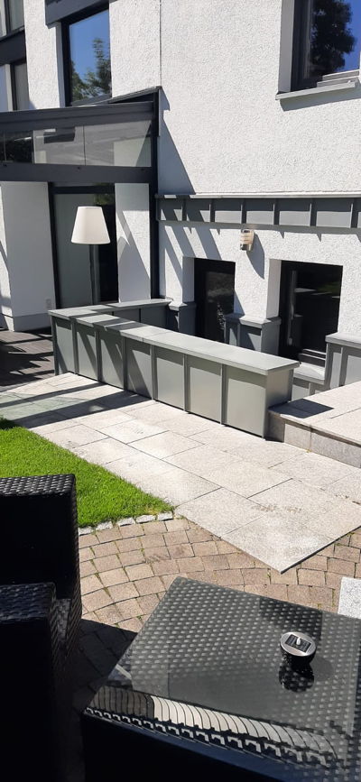 Ein Kellerabgang an einer Terrasse mit einer Mauerabdeckung und Wandverkleidung aus Zinkblech.